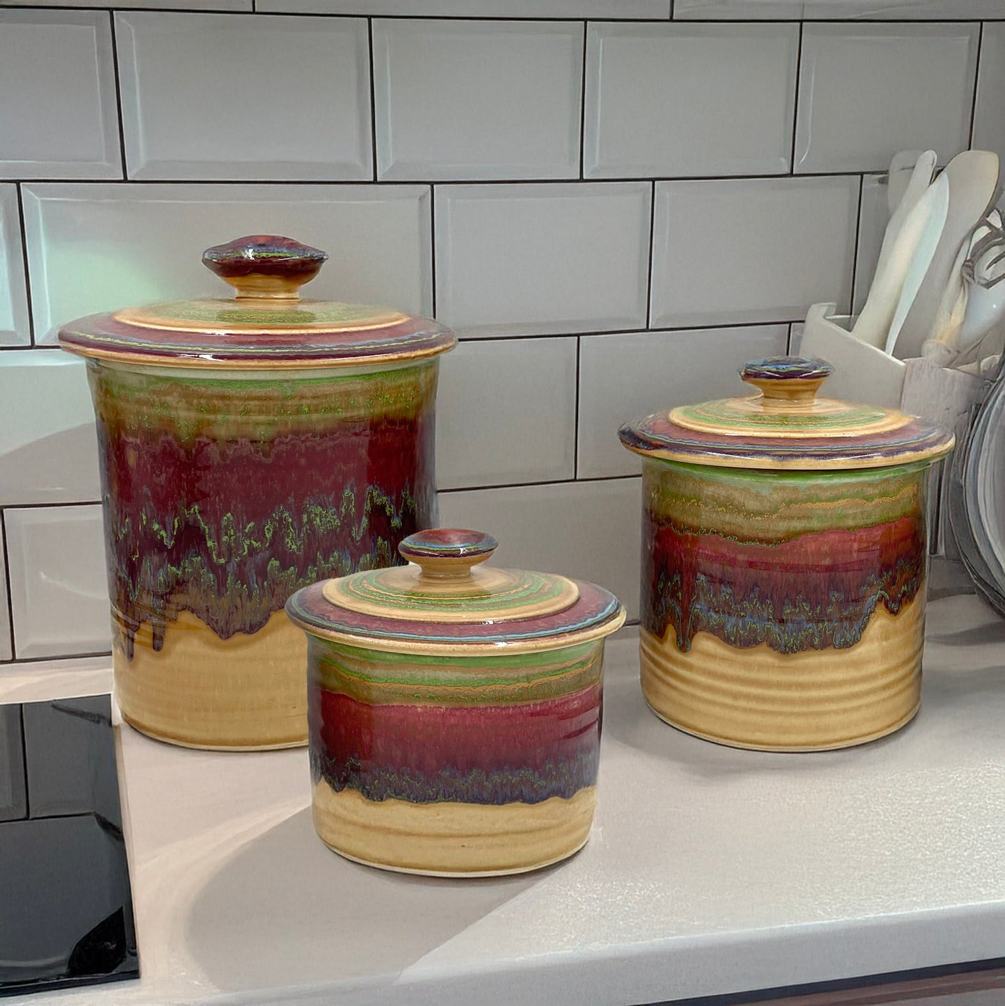 Set of three ceramic canisters with multicolored glaze on a kitchen counter.
