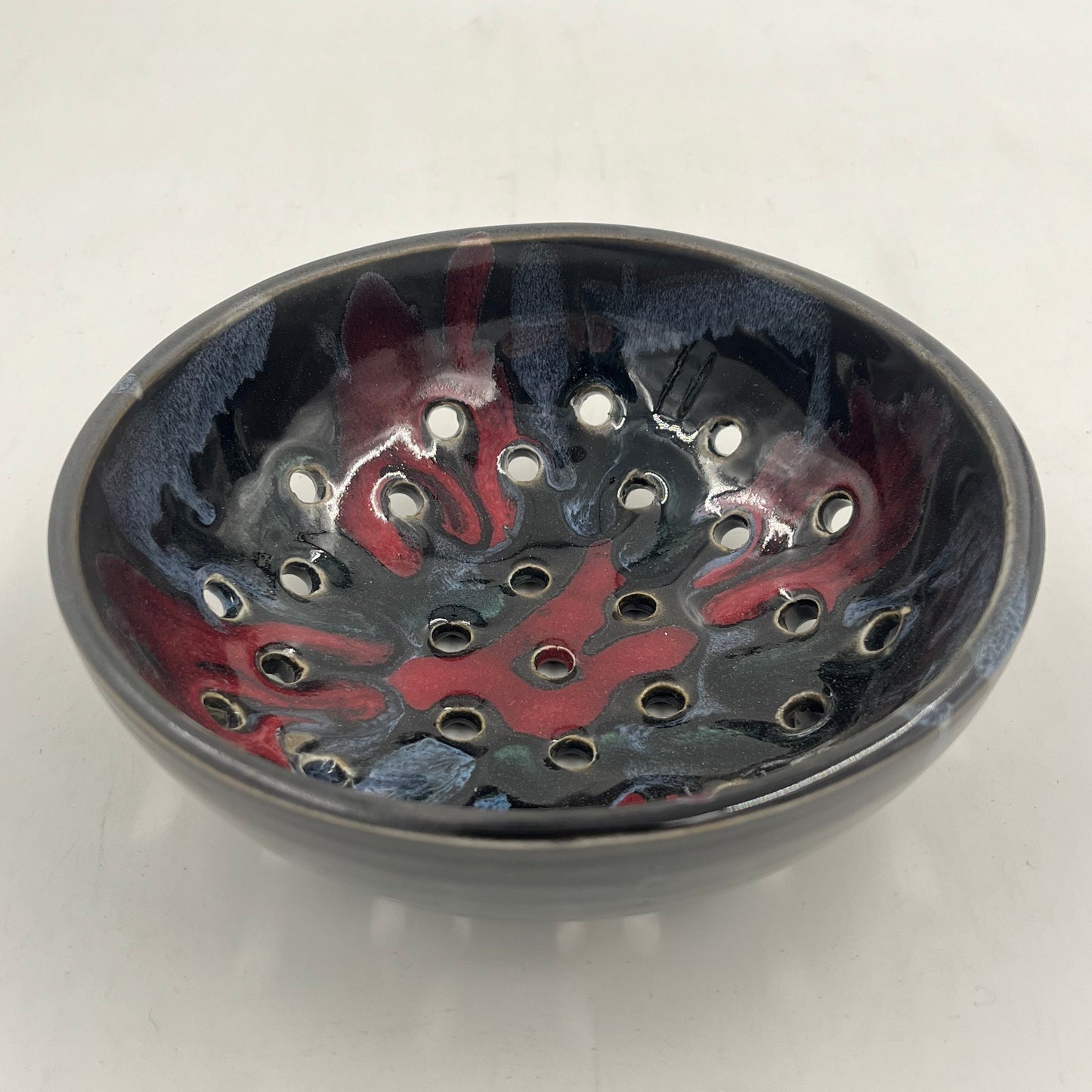 Round metallic object with red and black design on a white background