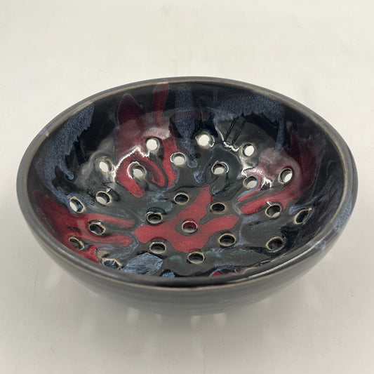 Round metallic object with red and black design on a white background