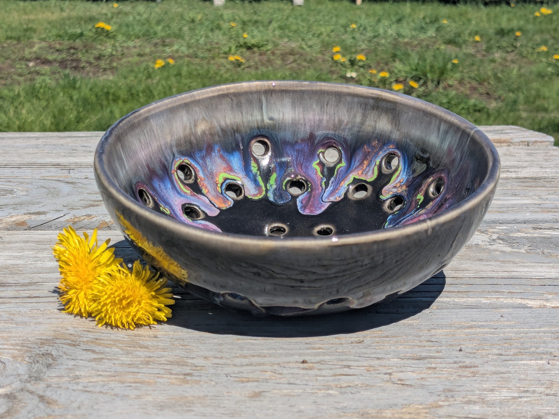Decorative ceramic bowl with colorful interior design on a wooden surface with dandelions.