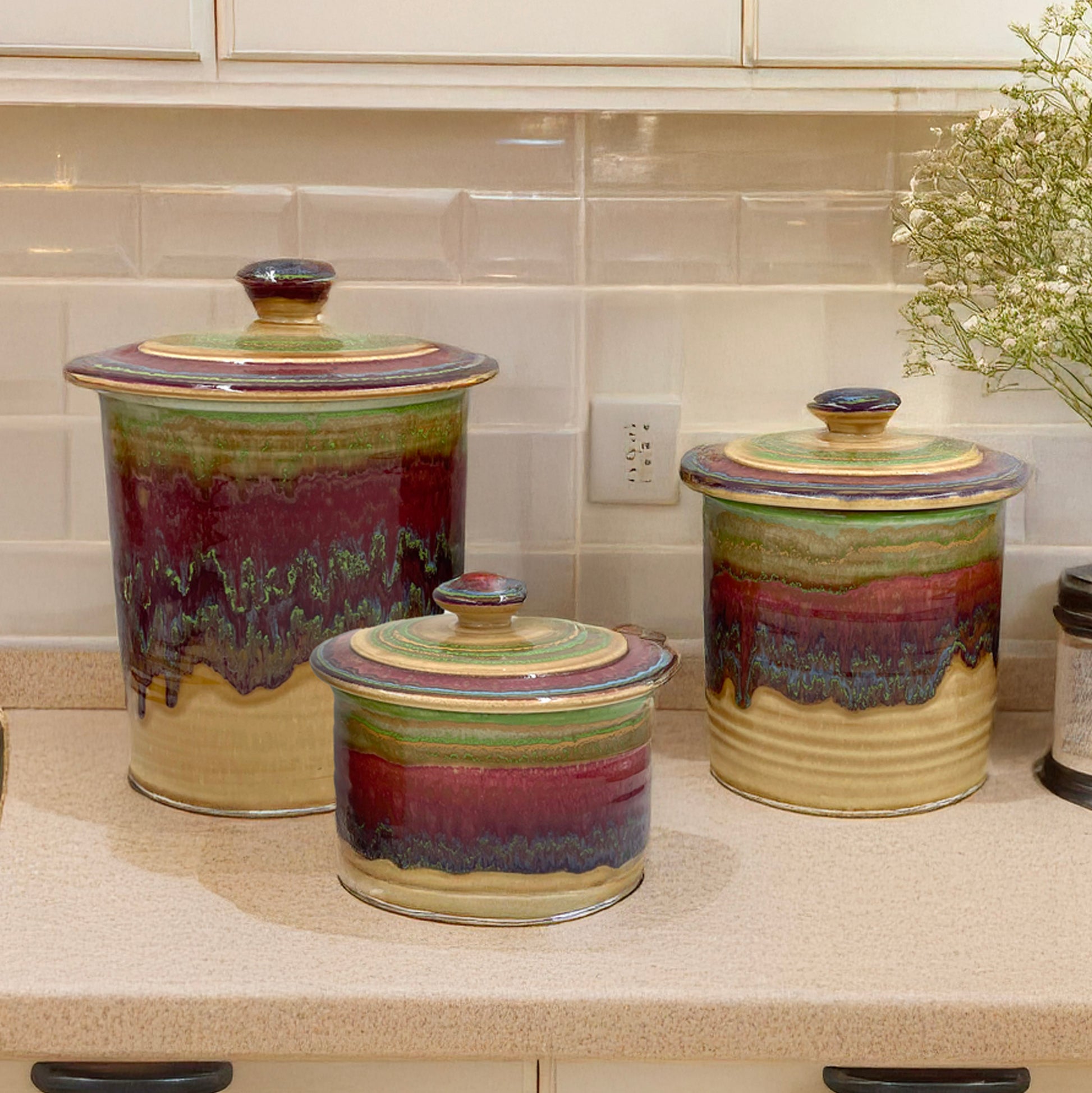 Set of three ceramic canisters with multicolored glaze on a kitchen counter.