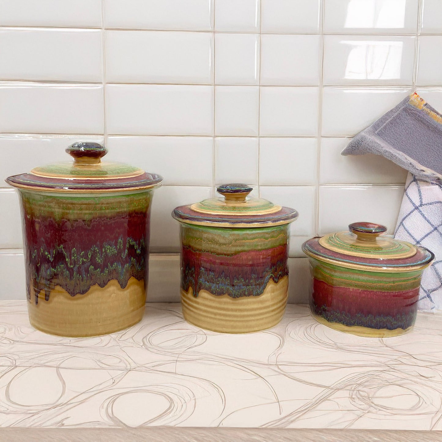 Set of three ceramic canisters with multicolored glaze on a kitchen counter.